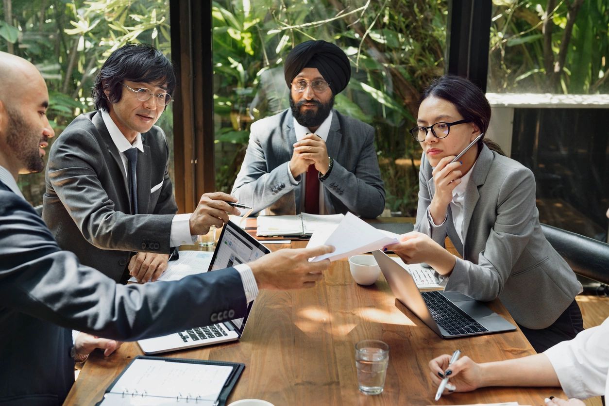 Multi-ethnic group of people at a table discussing a report