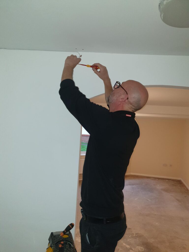 Philip Cox working on cable from ceiling