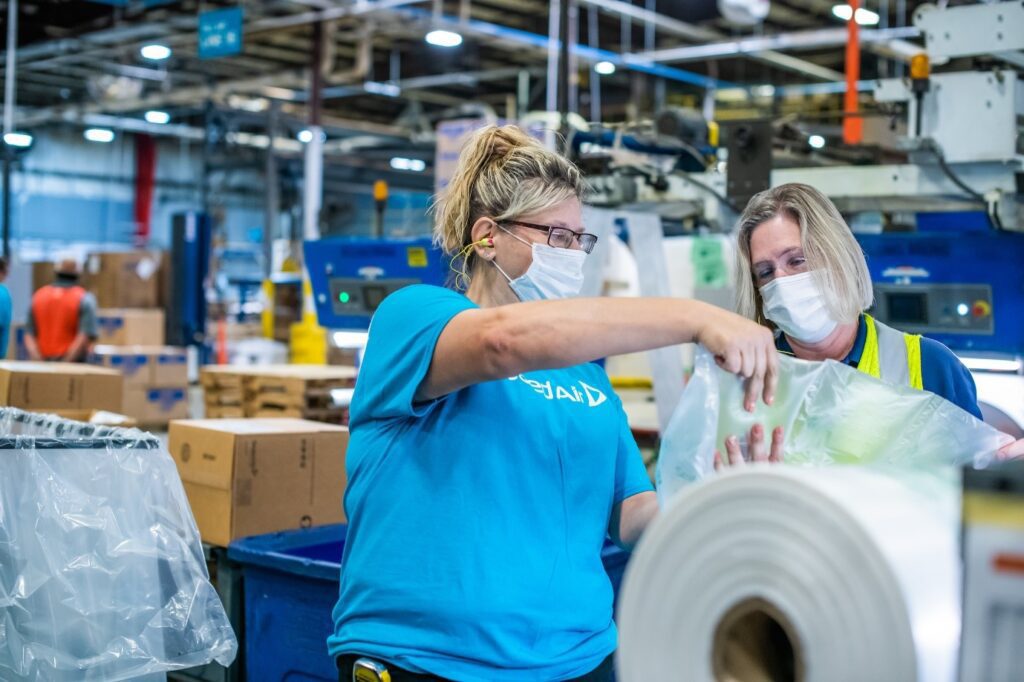 Two Sealed Air women engineers in factory with packaging production roll