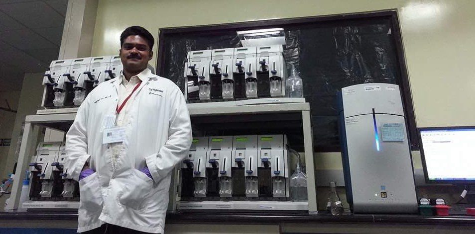Amith Oommen in lab in white coat