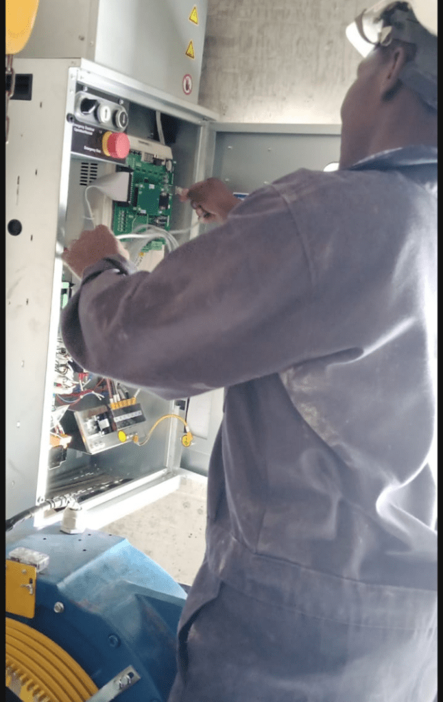 Kelvin Mwikya working on electrical control panel as an engineer servicing elevators and escalators 