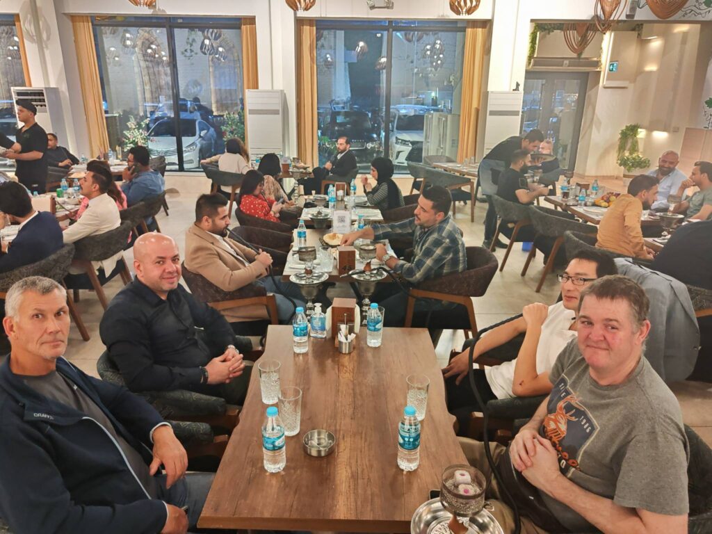 Sakher Fadaleh with GE engineers in Basra relaxing over dinner after a hard day installing a cyclotron system in Kawthar Hospital for cancer