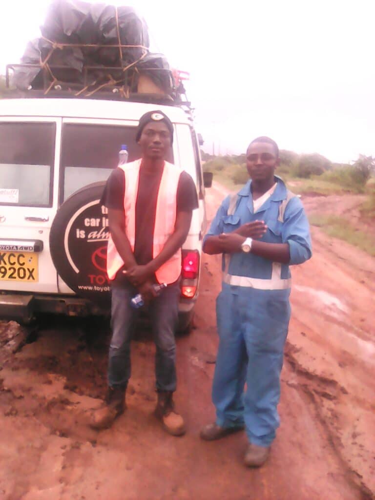 Thomas Okumu in the field with van and colleague on dirt track