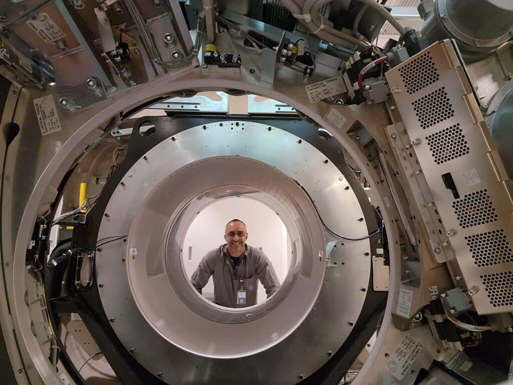Fausto Cruz healthcare field service engineer GE Healthcare looking through open MRI scanner