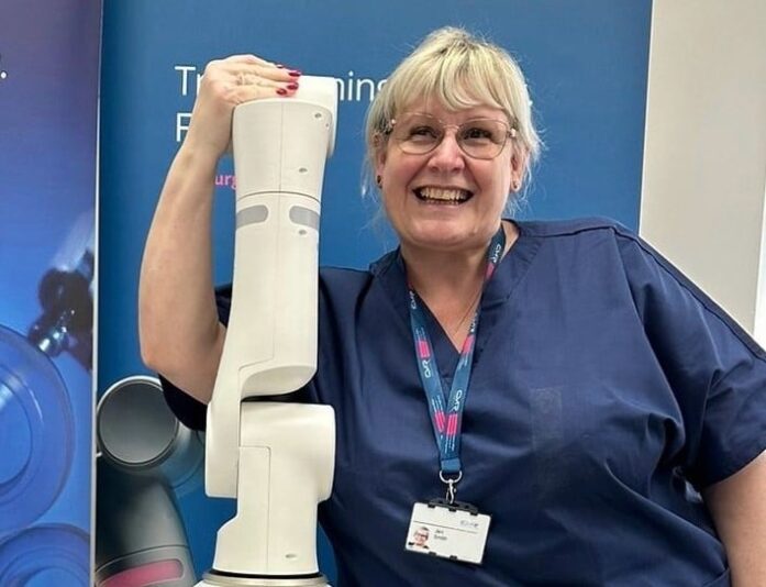 Jen Smith Medical Skills Trainer at CMR with robot arm blurred